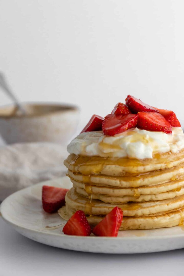 pancakes with coconut yogurt, strawberries and maple syrup
