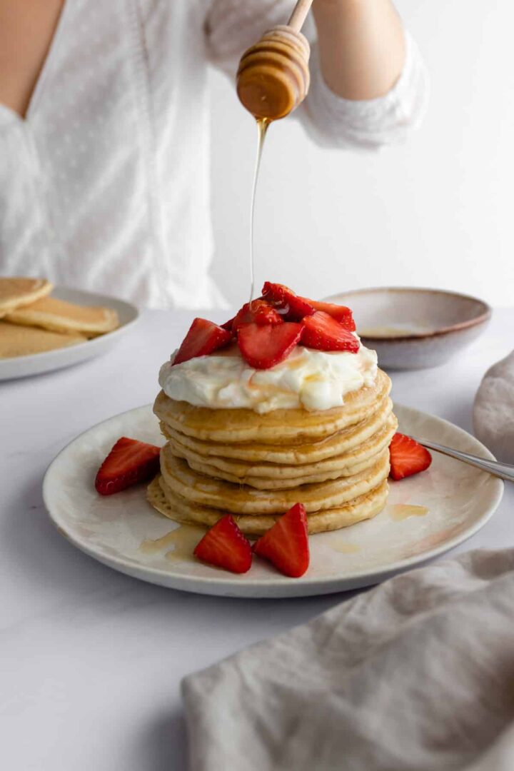 Rita in front of a marble table, a plate with a stack of pancakes on the table