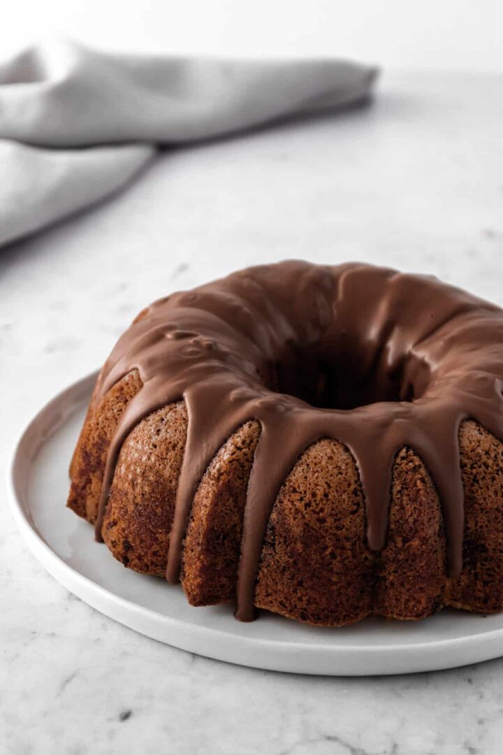 A big white plate with a marble cake topped with chocolate cream