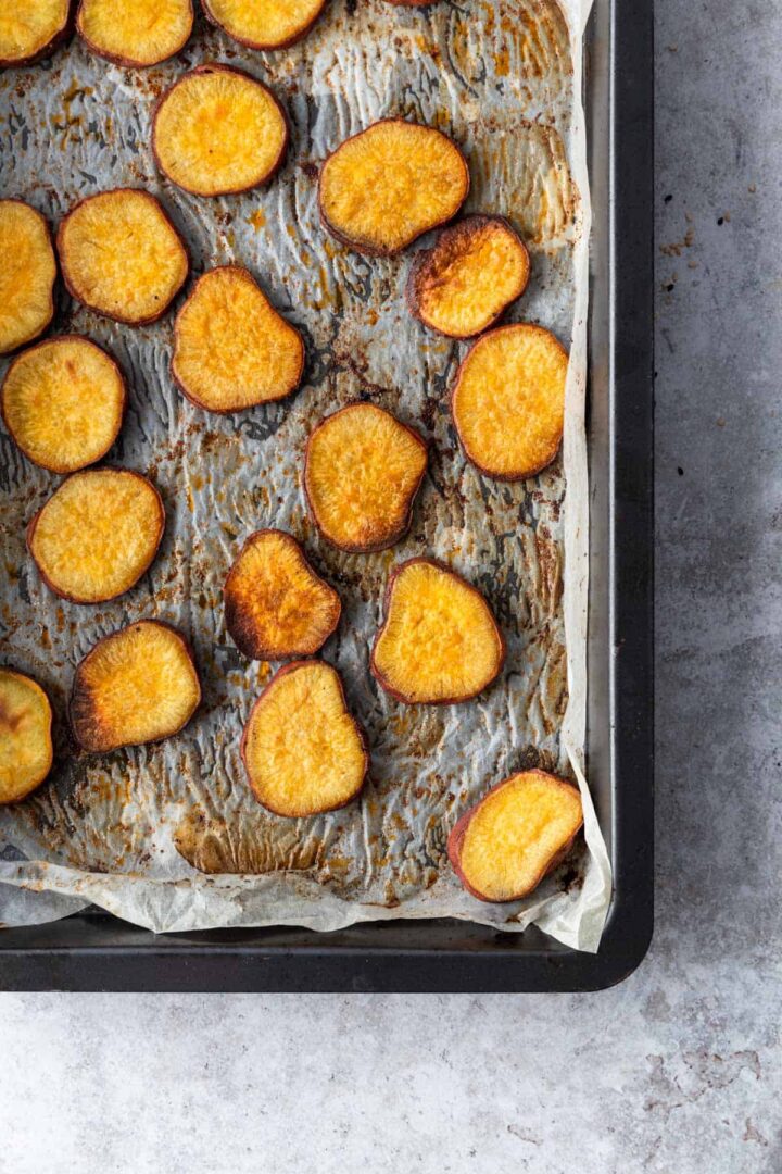 baking tray with parchment paper with baked sweet potato slices