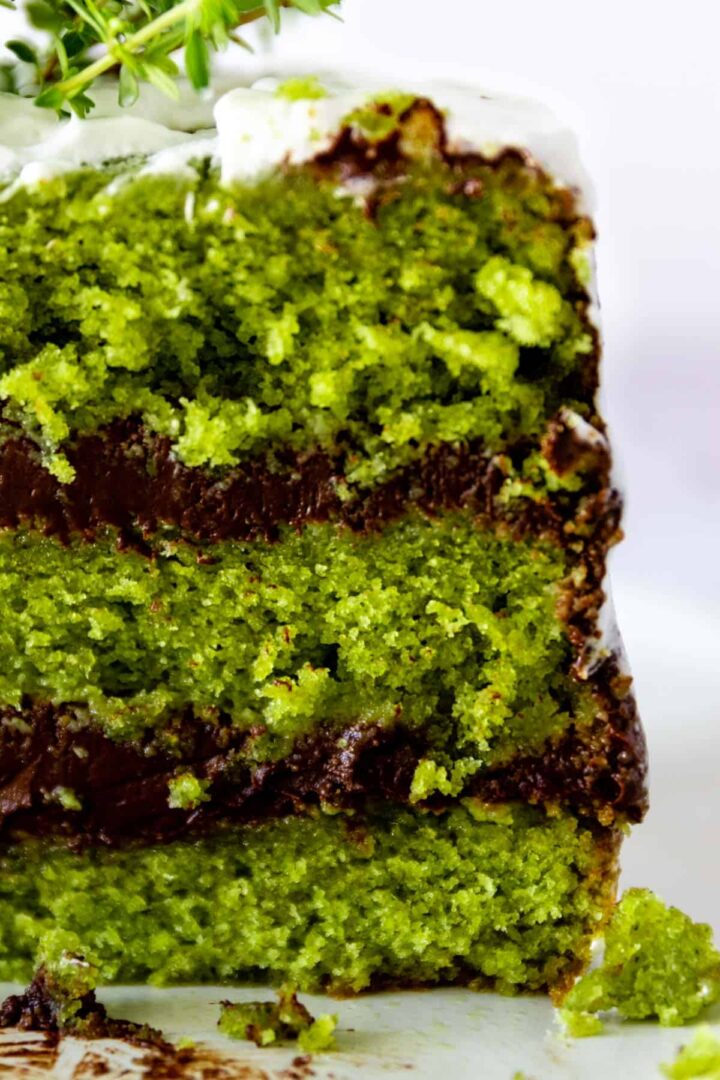 close-up of a three layered cake with three green cake layers and 2 layers of chocolate ganache