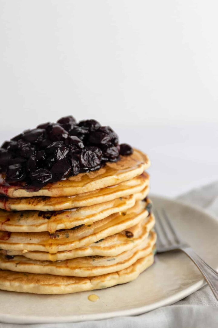 a stack of pancakes with blueberries and maple syrup on top