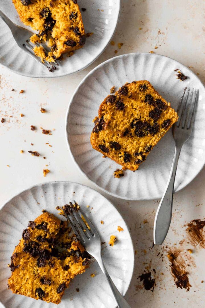 three slices of pumpkin bread served on plates with one fork each