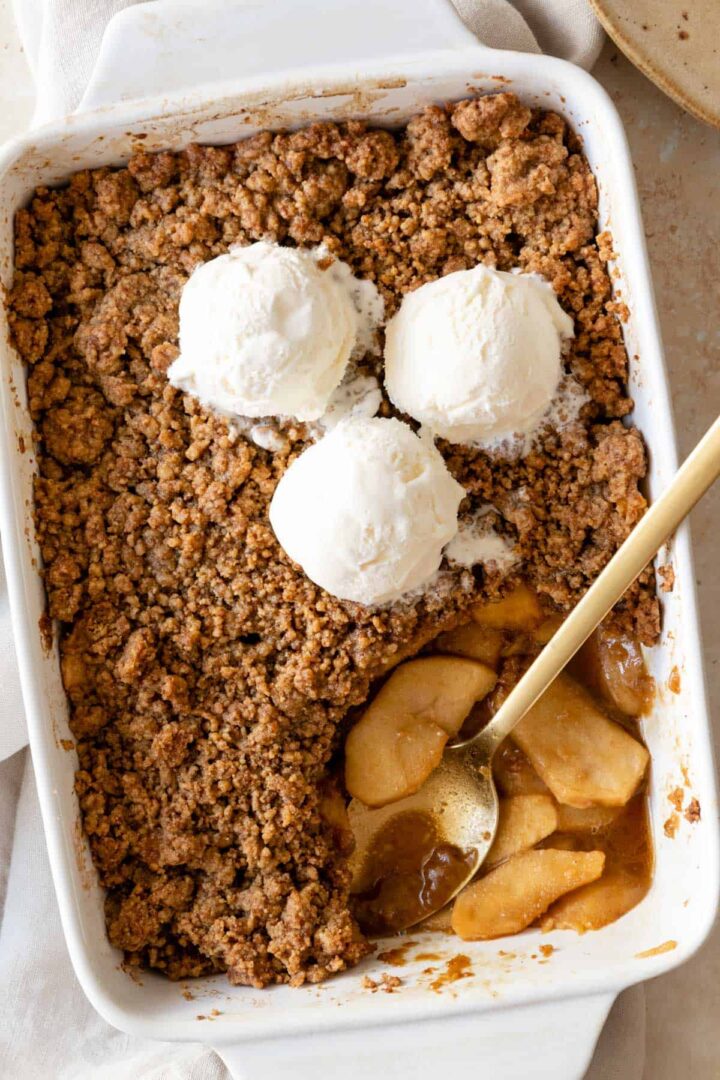 a baking dish with apple crumble and three ice cream bowls on top