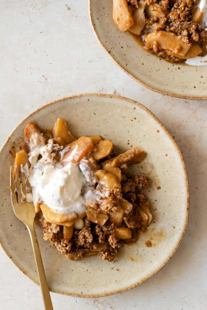a plate served with apple crumble and one bowl of ice cream melting on top
