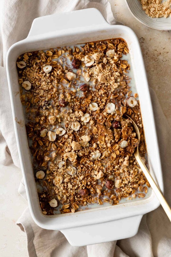 pumpkin baked oatmeal on a baking dish with a gold spoon on the side