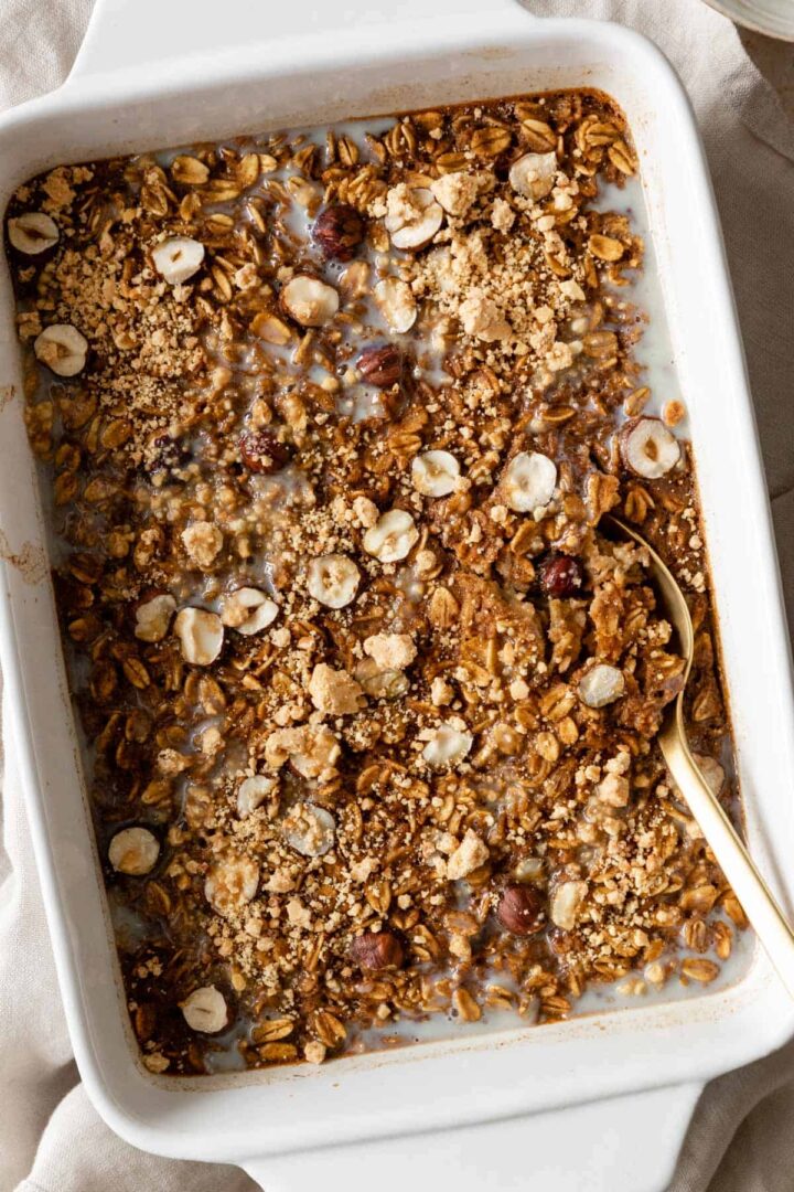 close-up of pumpkin baked oatmeal on a baking dish with a gold spoon on the side