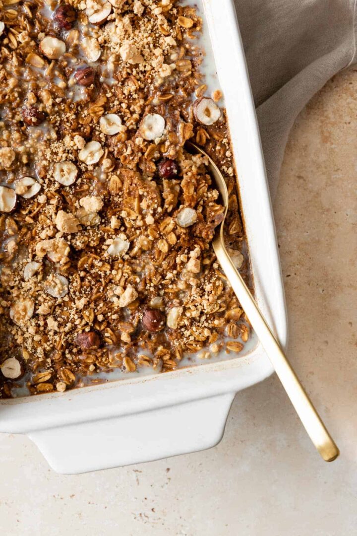 pumpkin baked oatmeal on a baking dish with a gold spoon on the side