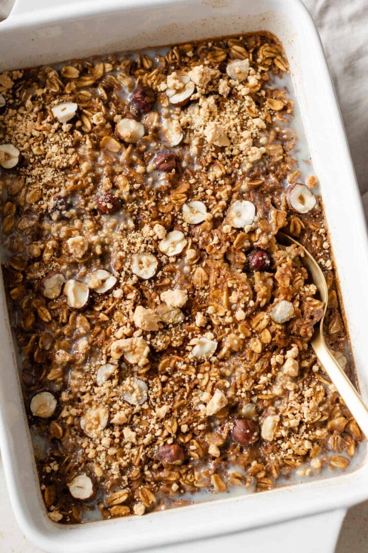 pumpkin baked oatmeal on a baking dish with a gold spoon on the side