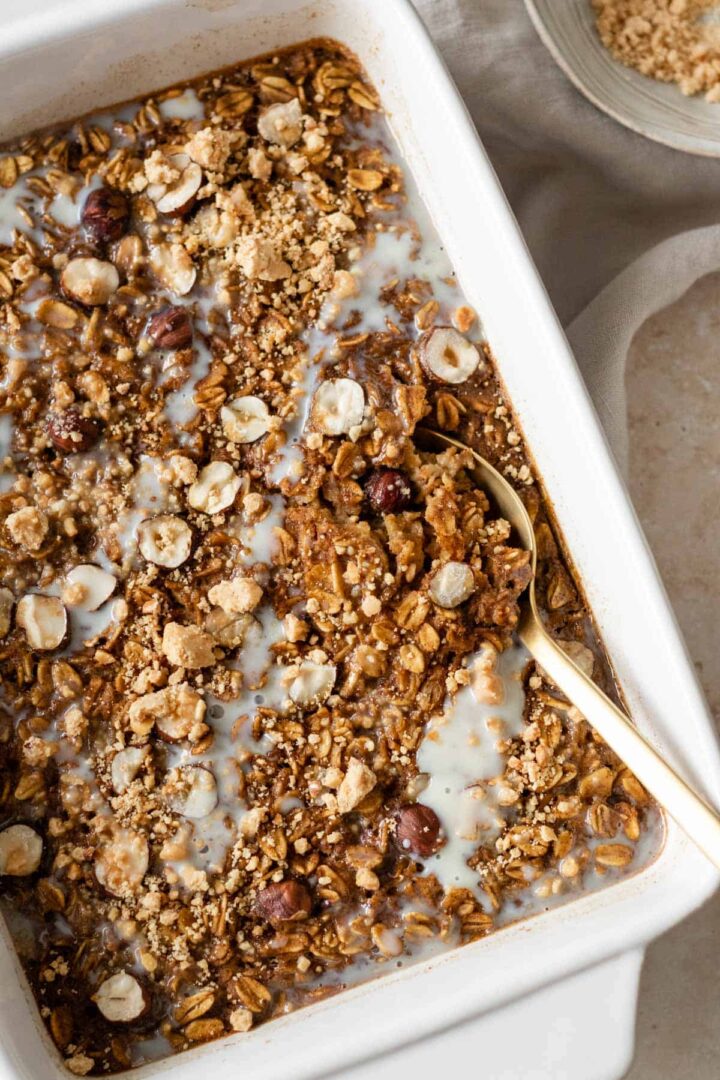 pumpkin baked oatmeal on a baking dish with a gold spoon on the side
