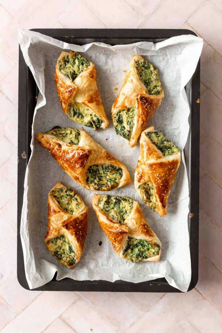 baking tray with white parchment paper and spinach puffs on top