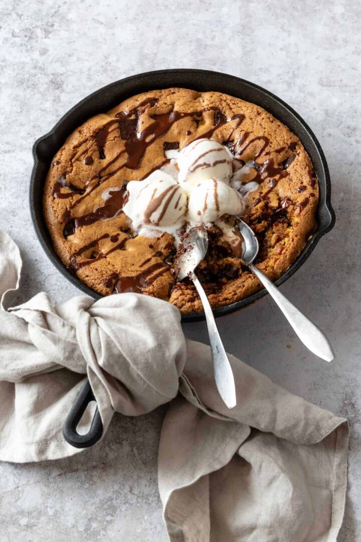 chocolate chip cookie skillet with ice cream and chocolate topping on top of a board
