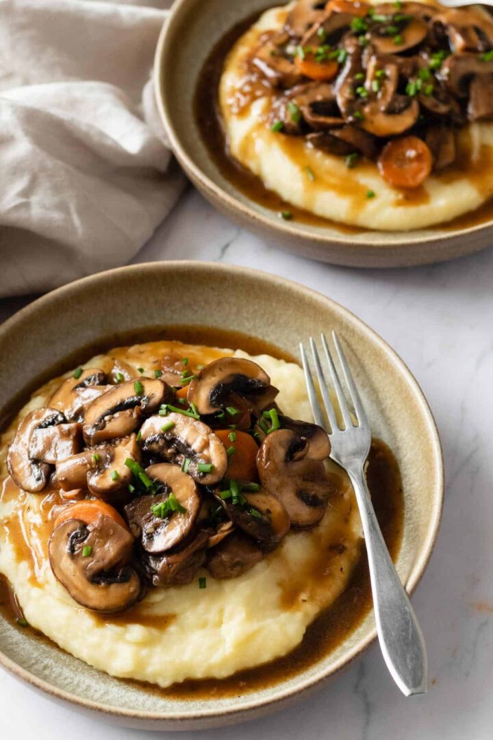 two plates served with mashed potatoes and mushroom bourguignon