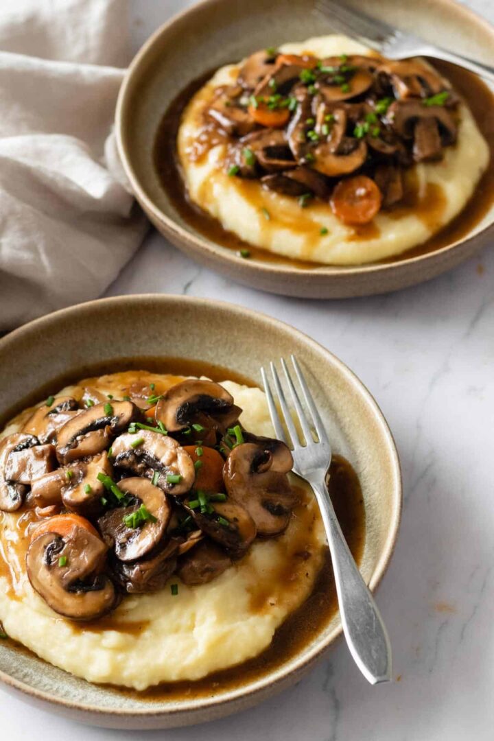 two plates served with mashed potatoes and mushroom bourguignon
