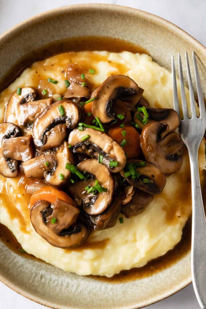 close-up of a plate served with mashed potatoes, sliced mushrooms, sliced carrots and chopped chives