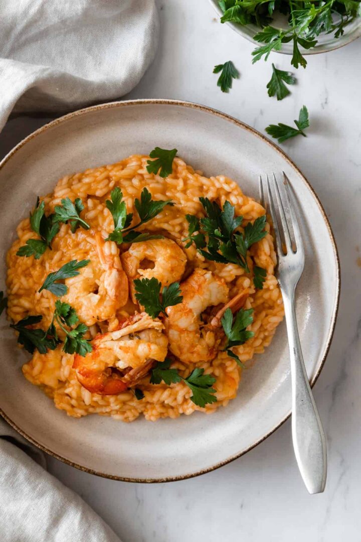 shrimp risotto with fresh coriander on a plate with a fork on the side