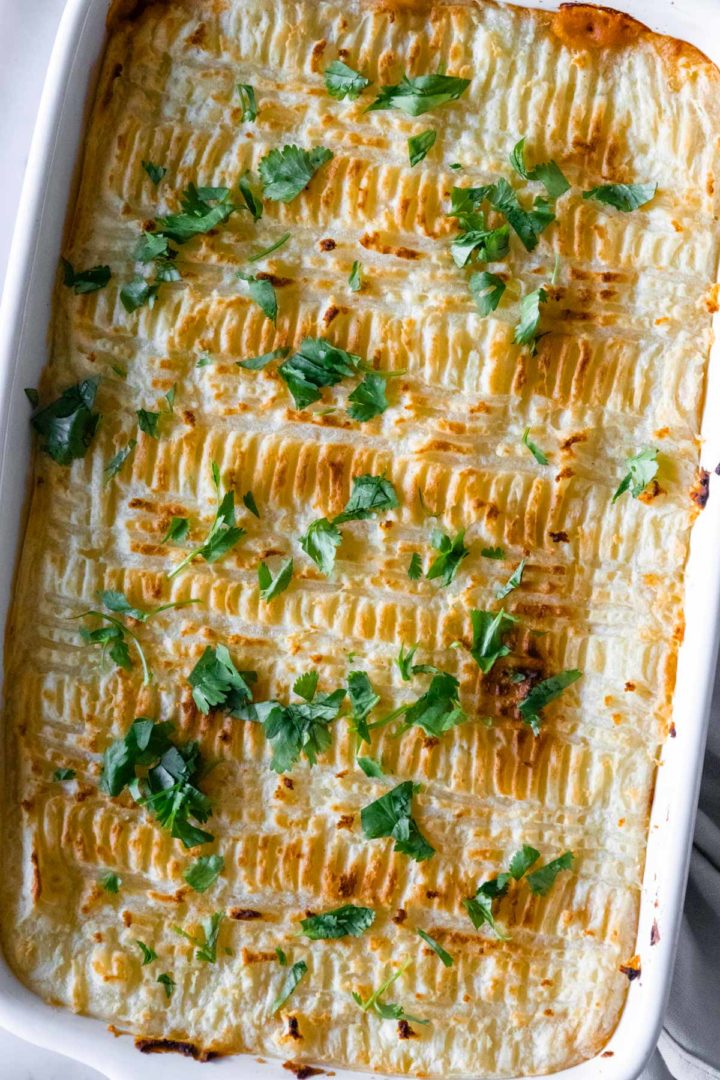 close-up of a baking dish with lentil Shepherd's pie with chopped coriander on top