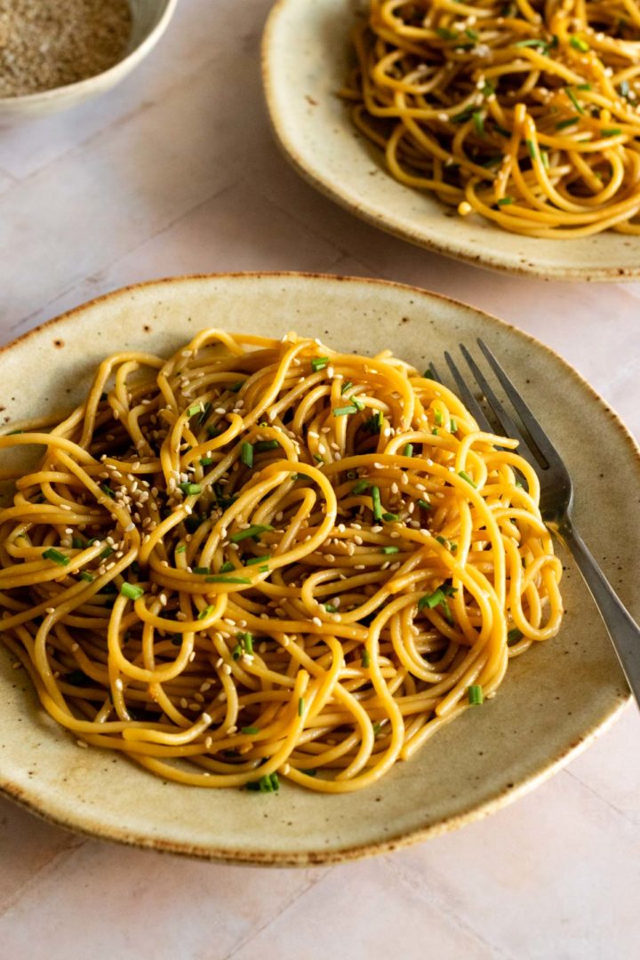 two plates served with sesame noodles, sesame seeds and chopped chives