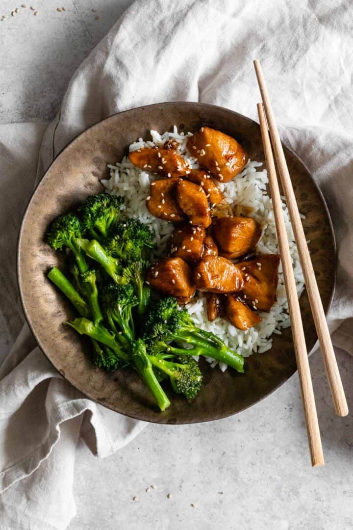 one bowl served with chicken teriyaki, rice, broccolini and garnished with sesame seeds