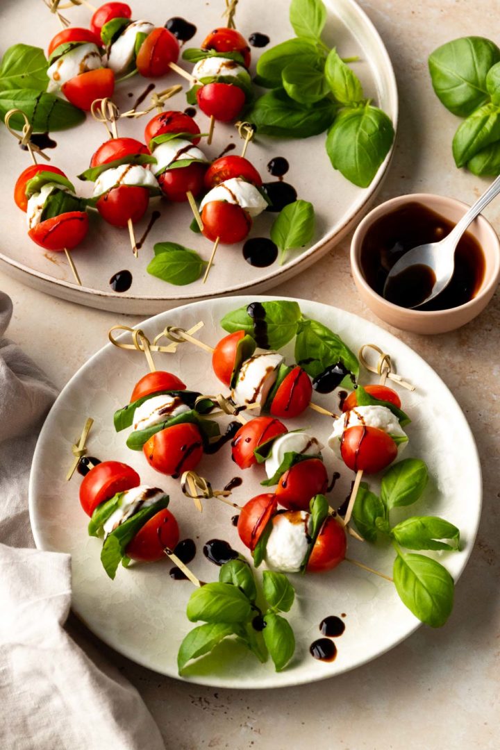 two plates served with skewers and a small bowl with balsamic glaze on the side