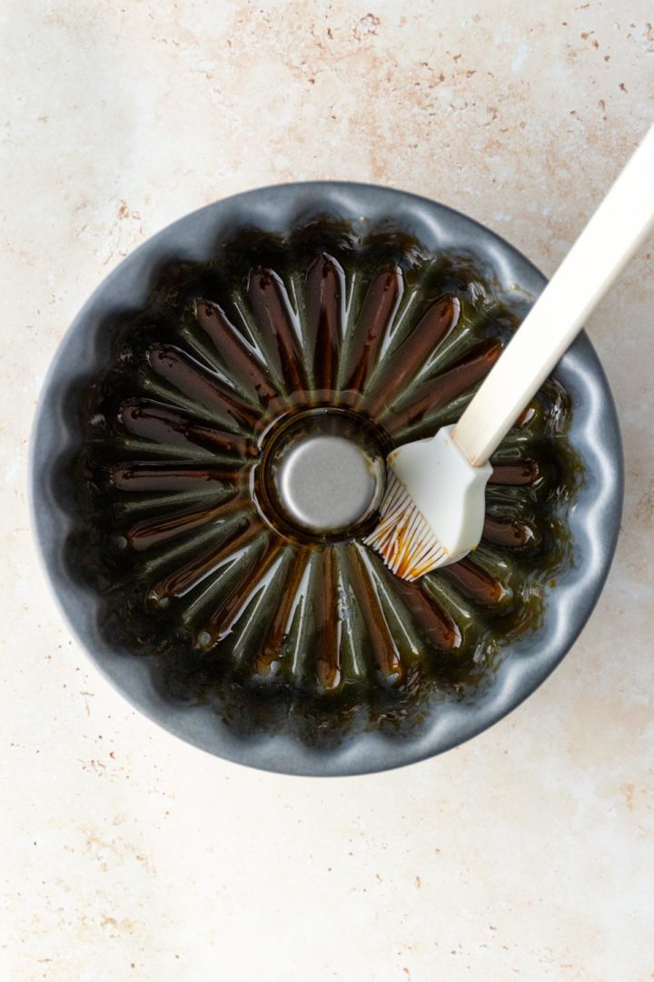 spreading the caramel sauce around the pan with the help of a silicone basting brush