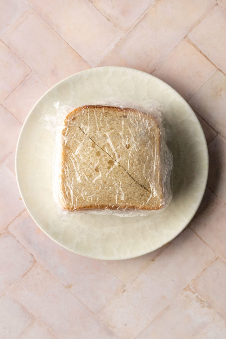 a plate with a sandwich wrapped in cling wrap