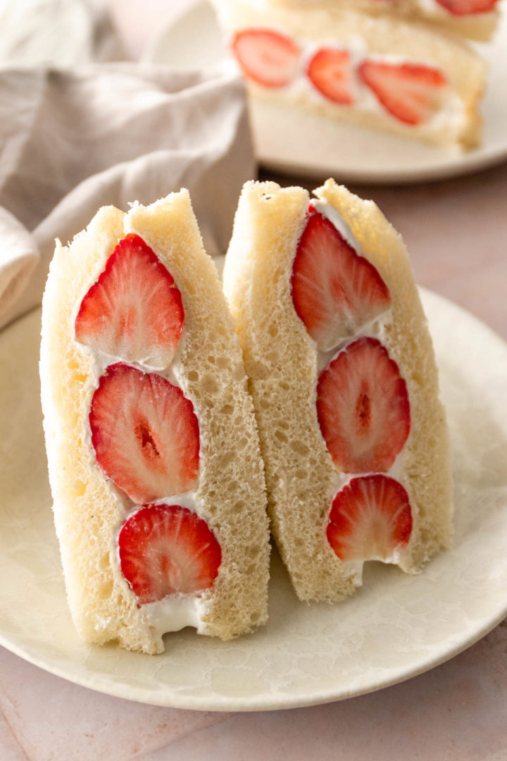 halves of Japanese sandwich with whipped cream and strawberries on a plate