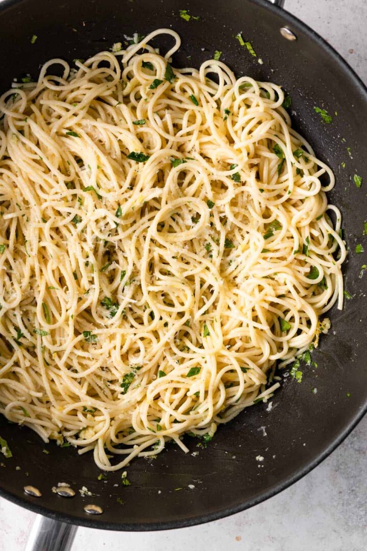 a wok with spaghetti with parmesan cheese, lemon zest and chopped parsley