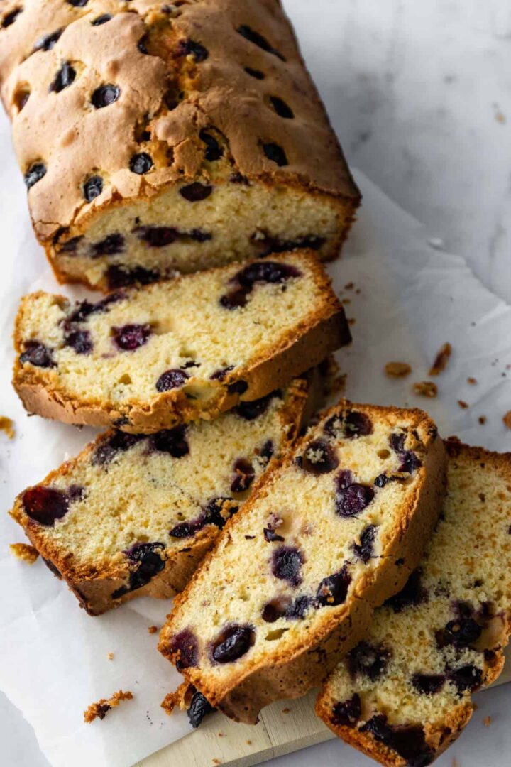 a lemon blueberry bread on top of a wood board and parchment paper