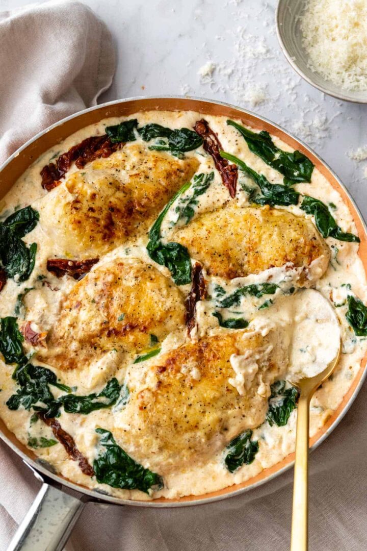 creamy Tuscan chicken on a pan with sun-dried tomatoes, baby spinach and parmesan cheese