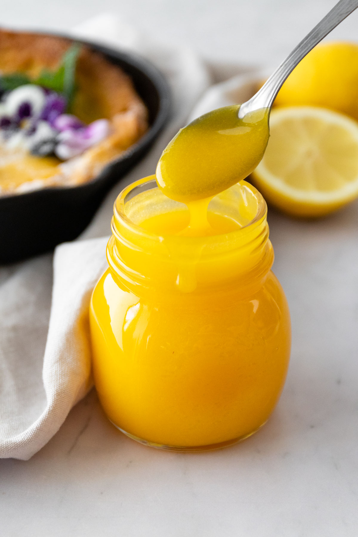 a small glass jar with lemon curd and a spoon with lemon curd